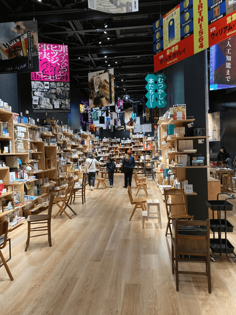 Bookshelf store interior with shoppers and hanging banners in a modern bookstore.
