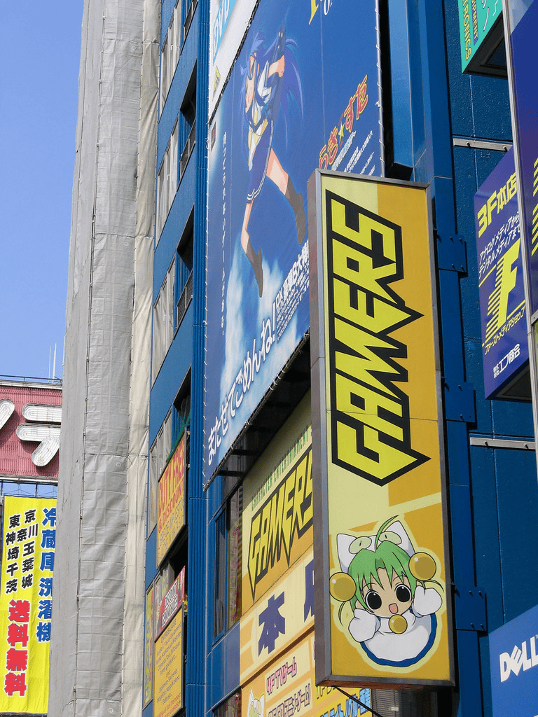 Anime and gaming shop sign, Tokyo city street scene, vibrant commercial area, colorful advertisements.