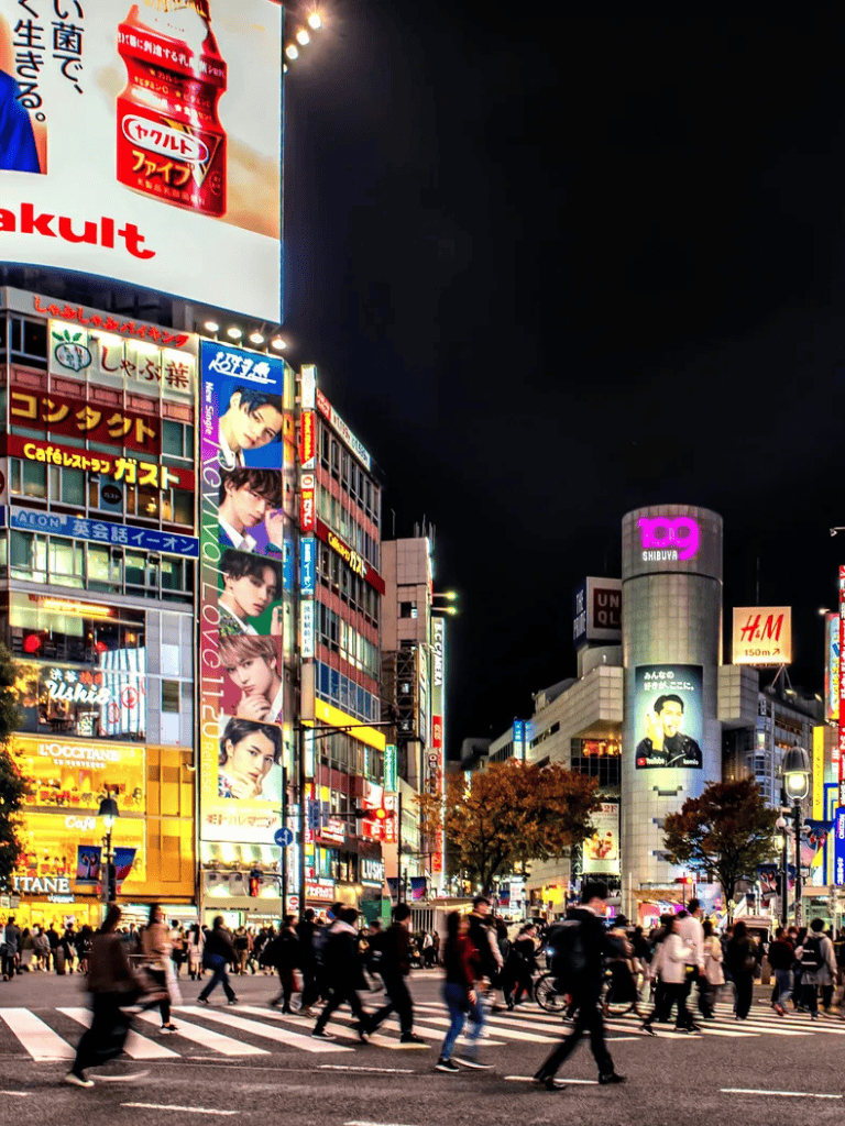 Bright Tokyo city street at night with neon signs and busy pedestrians.