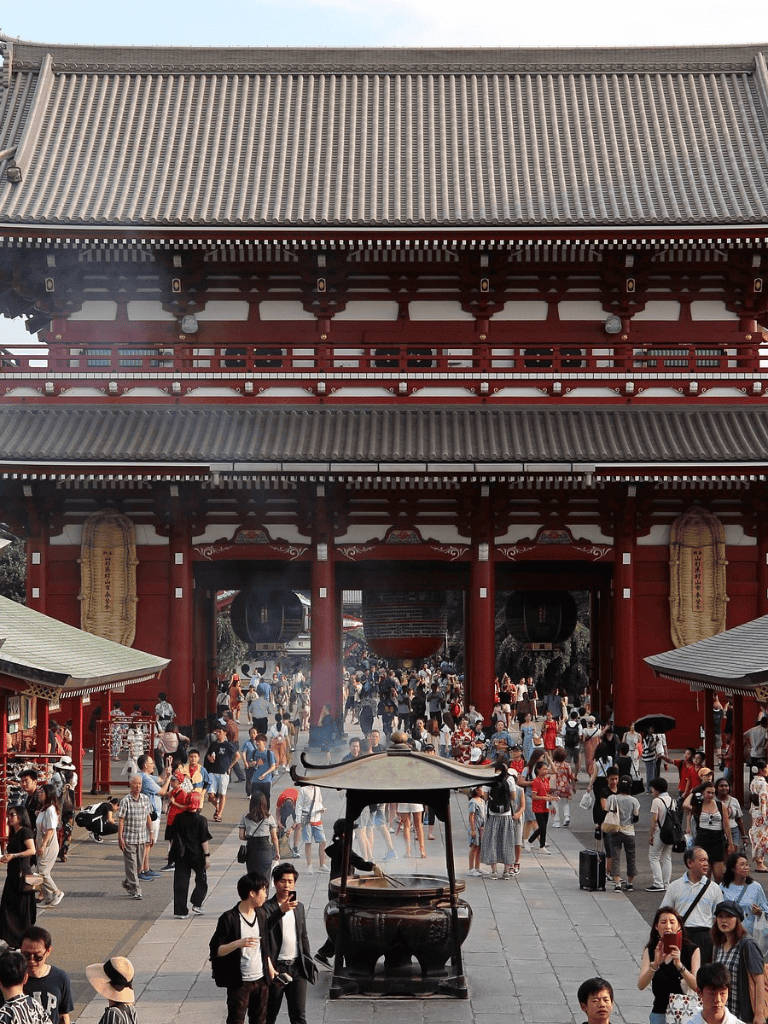 Outdoor temple entrance with traditional architecture, crowded with visitors and worshippers.