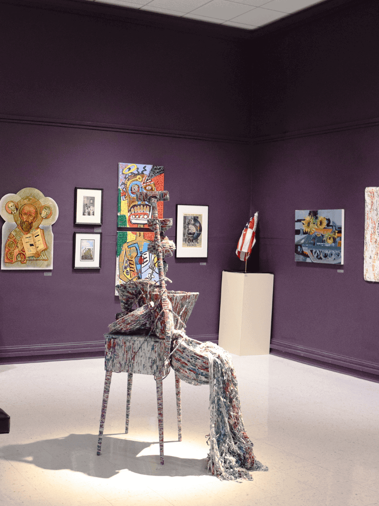 Colorful contemporary art installation in a gallery with framed artwork on purple walls.