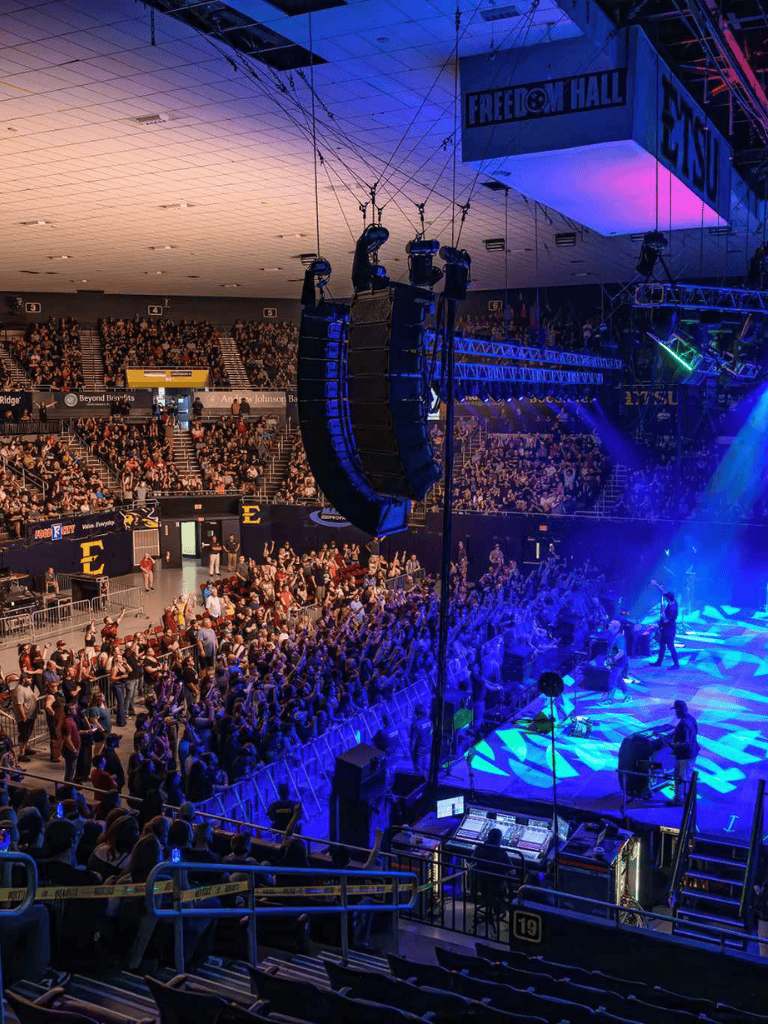 Crowd at a live concert venue with stage lighting and sound equipment, highlighting QuestForDirections event.