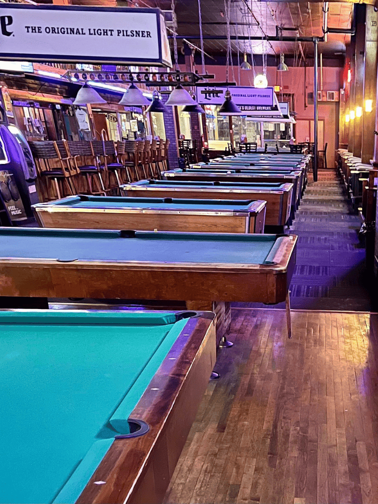Bright indoor sports bar with pool tables and high stools, inviting for game nights and social gatherings.