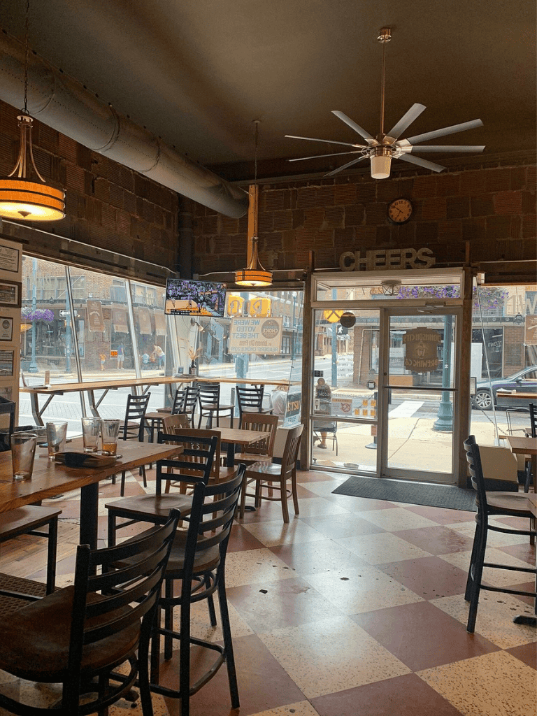 Cozy restaurant interior with brick walls, wooden tables, and large windows for a welcoming dining experience.