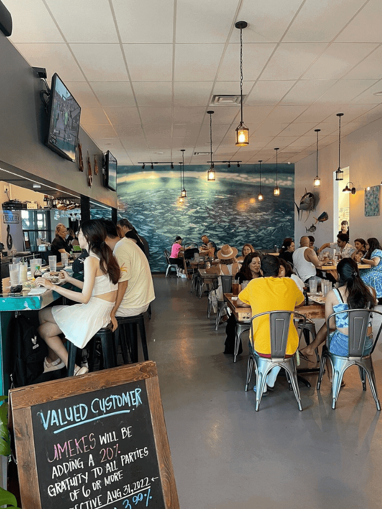 Brightly lit seafood restaurant with ocean-themed mural and customers enjoying meals.
