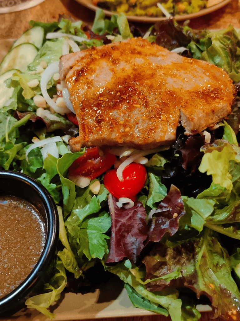 Seared pork chop over mixed greens salad with cherry tomatoes and balsamic dressing.