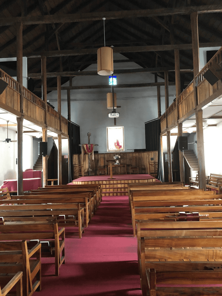 Wooden church interior with altar, pews, and soaring ceiling, peaceful worship space, QuestForDirections, spiritual journey, church architecture.