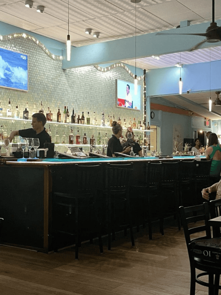 Bartenders preparing drinks at a modern, cozy bar with a vibrant, inviting atmosphere.