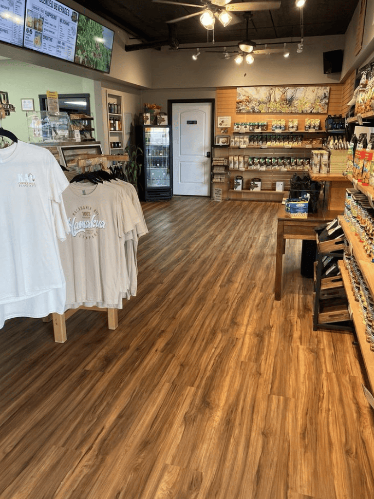 Handcrafted coffee and retail store interior with wooden flooring, merchandise shelves, and digital menu displays.
