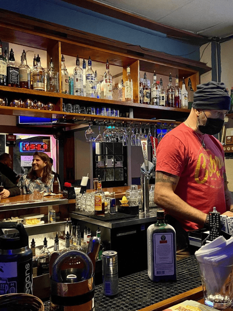 Enjoying drinks at a cozy bar with a wide selection of liquor bottles and a lively atmosphere.