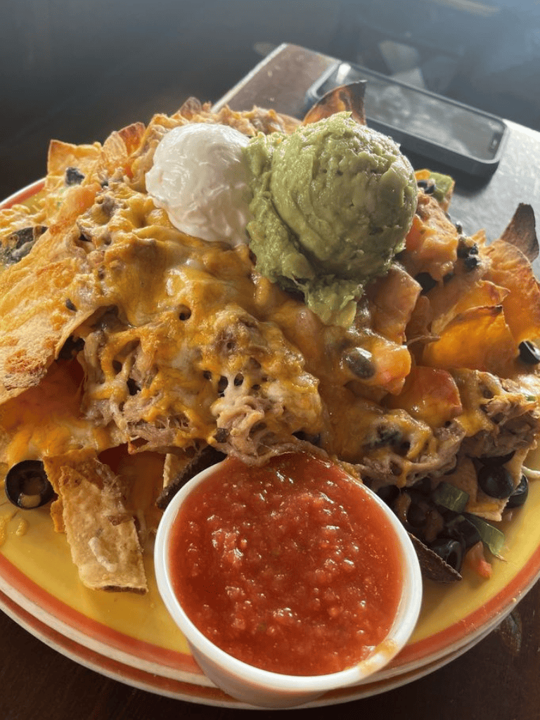 Cheesy nachos topped with sour cream, guacamole, and salsa, served with crispy tortilla chips.