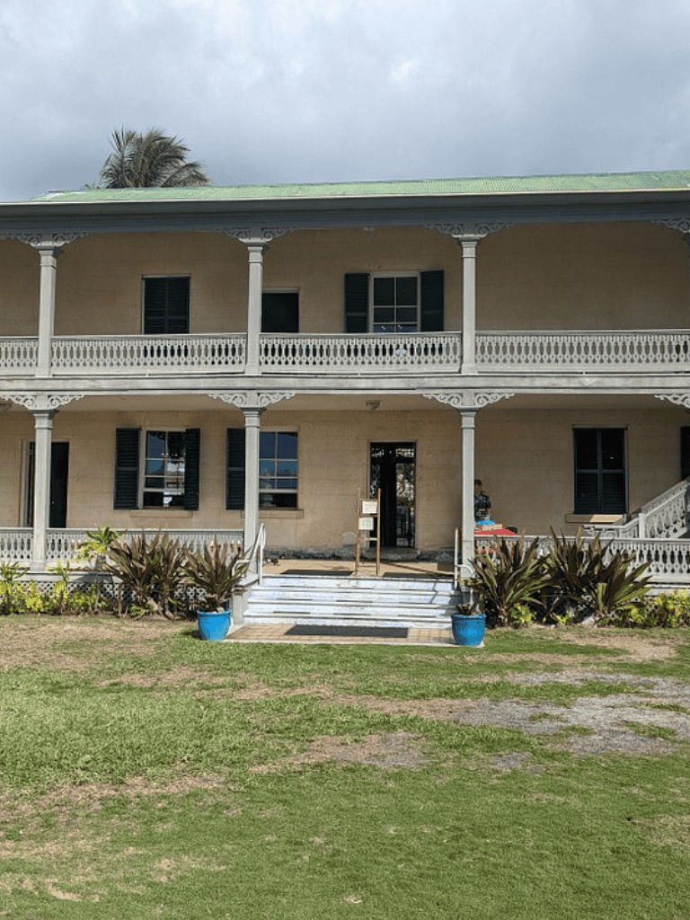 Historic building with a two-story porch and lush landscaping.