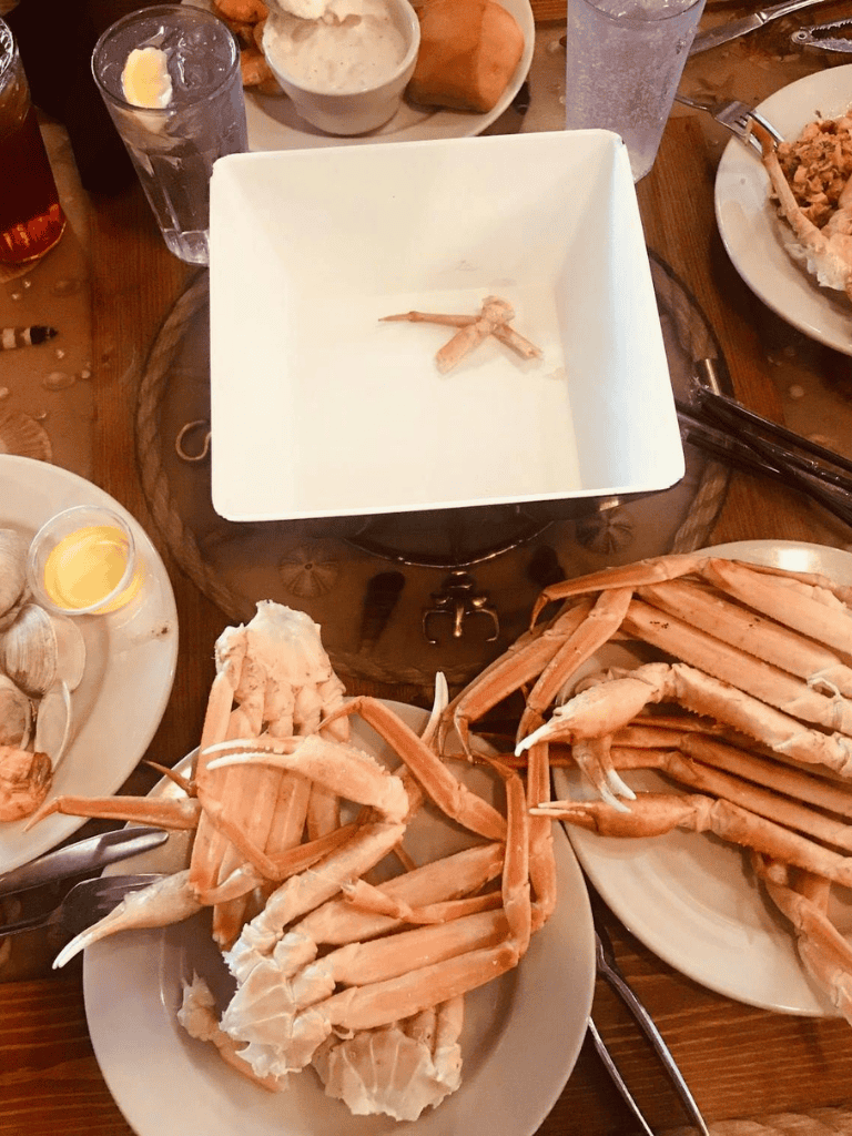 Boiled crab legs with seafood dipping sauces, served on plates at a seafood restaurant.