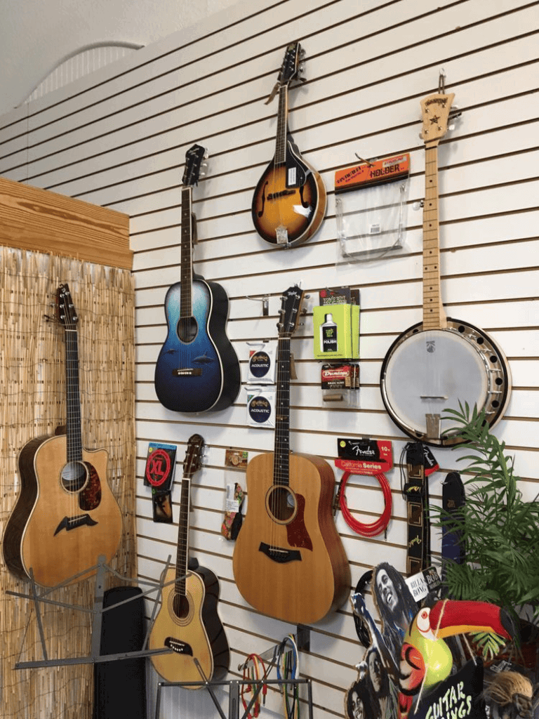 Guitar and banjo display in music store with selection of acoustic and electric instruments.