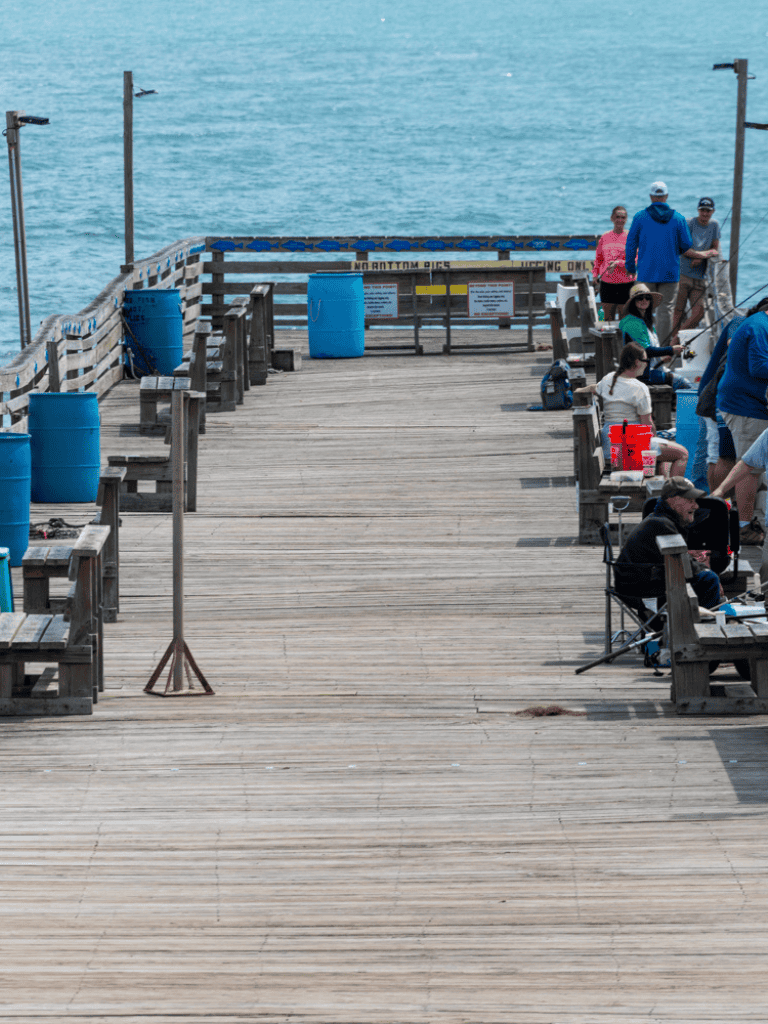 Relaxing pier scene with people fishing and enjoying ocean views at Quest for Directions.