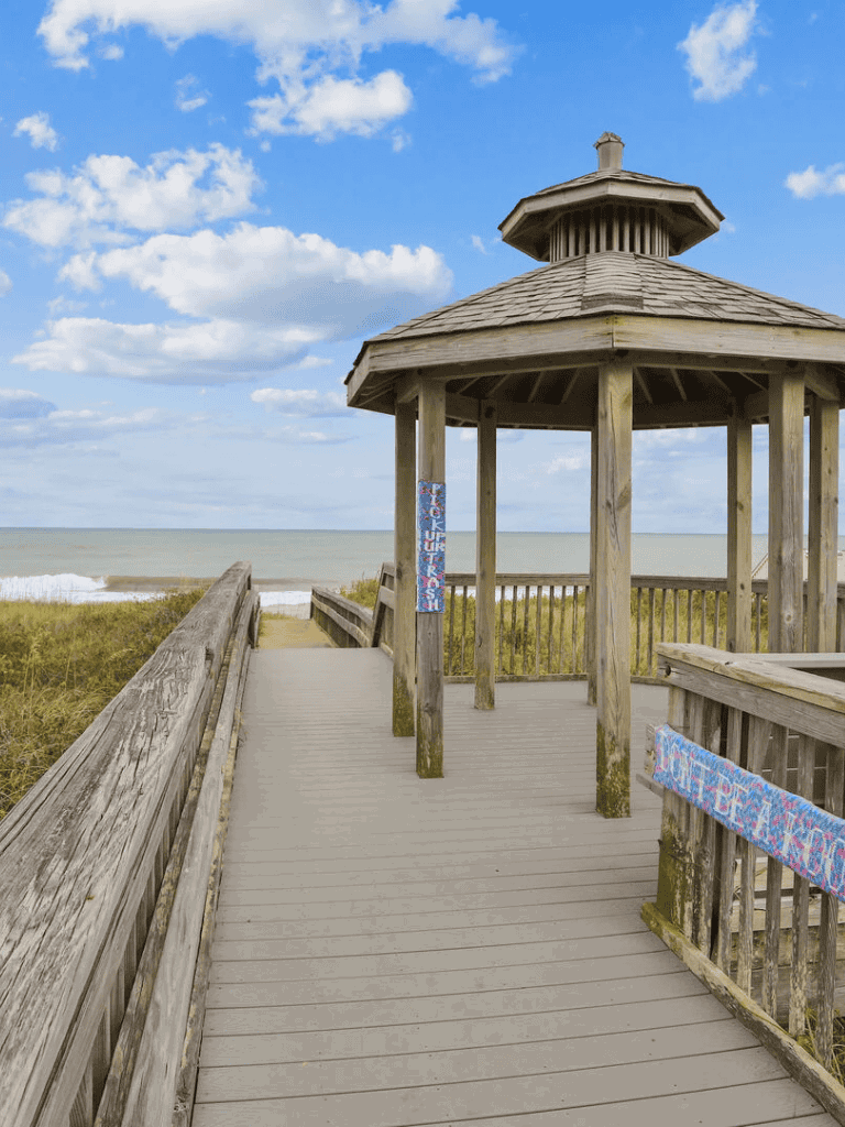 Bright beach gazebo on wooden walkway overlooking the ocean, perfect for seaside relaxation and scenic views.