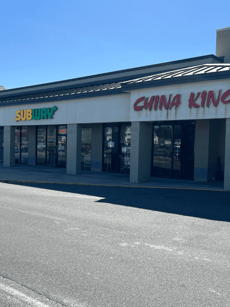 Subway and China King restaurant storefront in shopping plaza, sunny day.