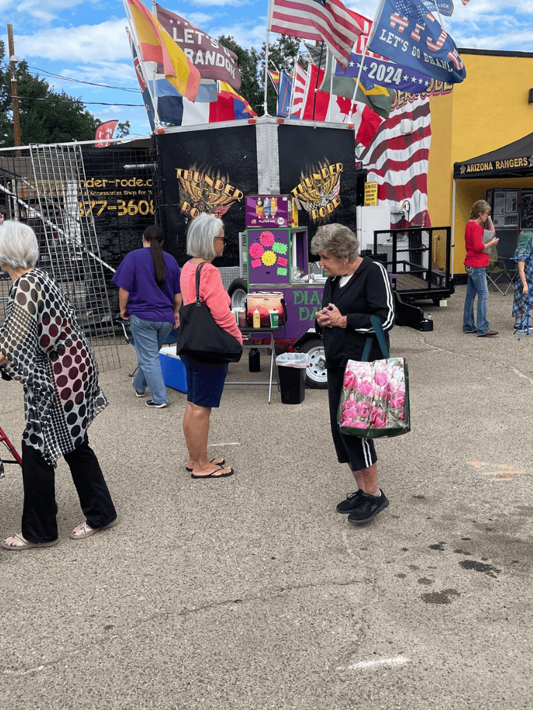 Colorful fairground scene with popcorn stand, flags, and people enjoying a day out.