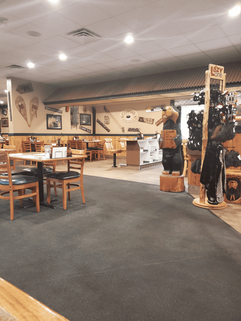 Cozy restaurant with wooden furniture, rustic decor, and black bear statues. Ideal for dining and gathering in a warm, inviting atmosphere.