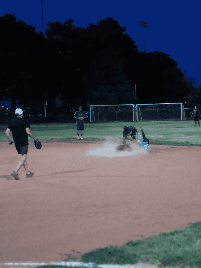 Player sliding into base during a nighttime softball game.