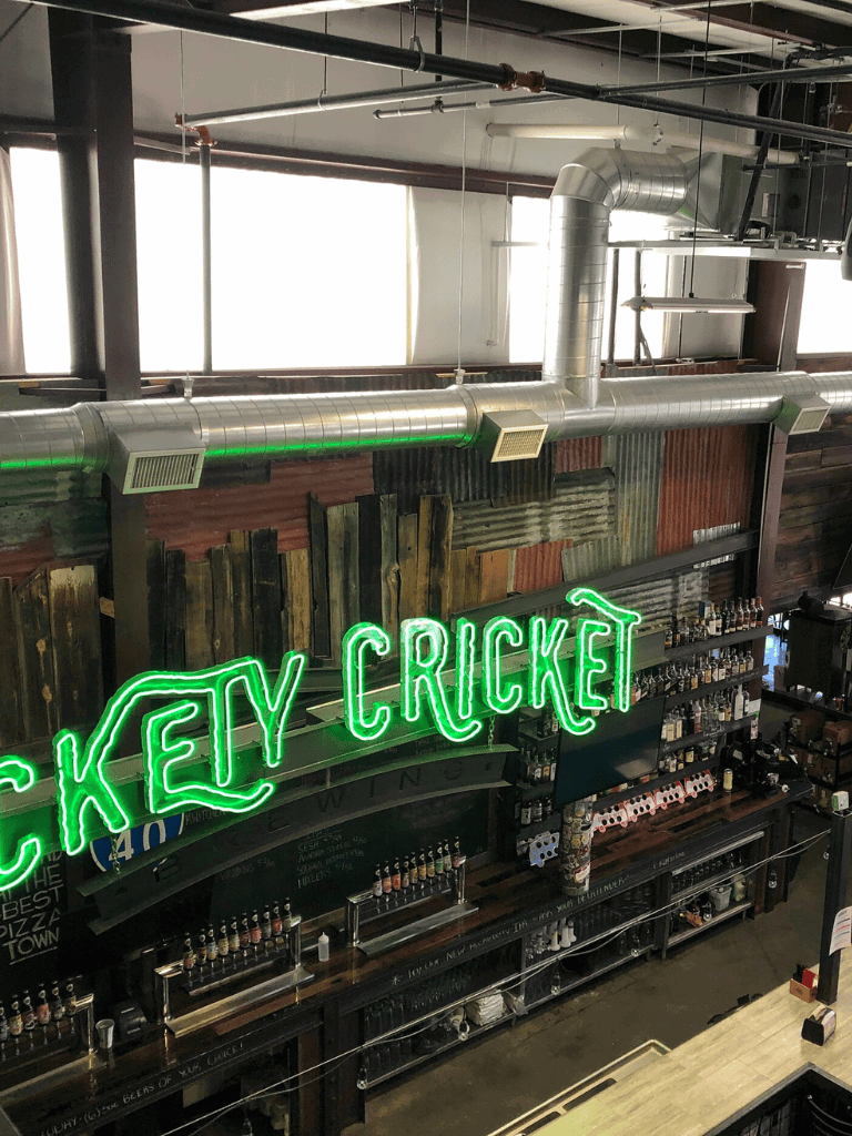 Neon sign reading "KEY CRICKET" in a trendy bar or restaurant atmosphere.