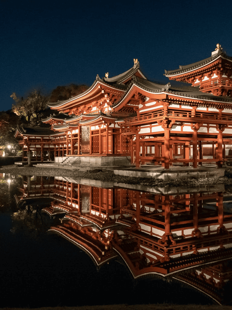Stunning illuminated traditional Japanese temple at night with reflection in water, scenic cultural landmark.