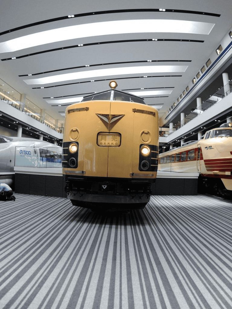 Vintage train display inside transportation museum with modern arch ceiling.