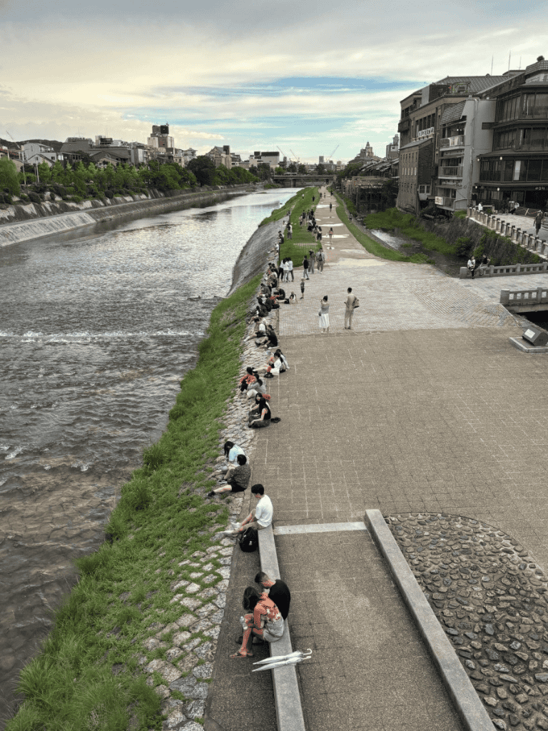 People fishing along a river promenade in an urban area.