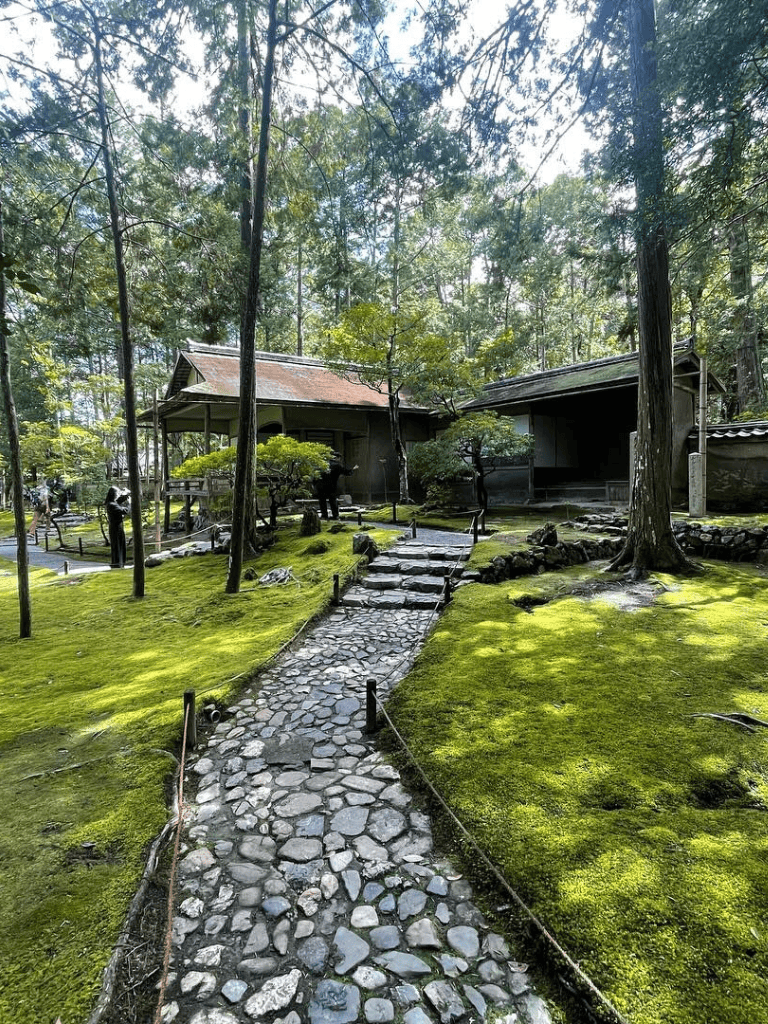 Serene Japanese garden with traditional wooden structures and lush greenery.