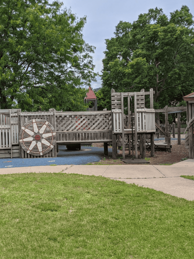 Wooden playground structure with trees in the background, perfect for children's outdoor activities and family fun.