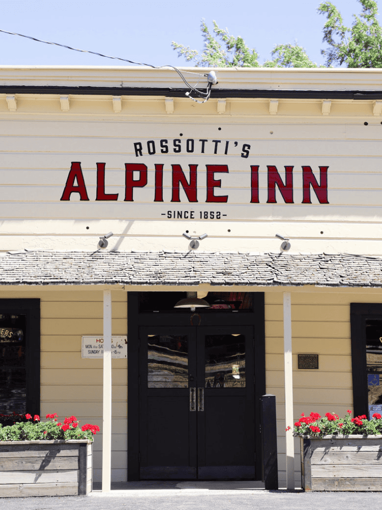 Alpine Inn historic mountain lodge in Rossotti's since 1852, charming outdoor entrance with flower planters.