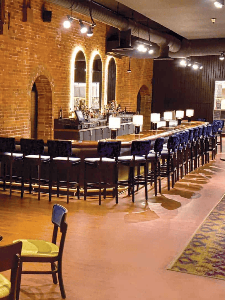 Cozy bar with brick walls, illuminated arches, and a welcoming seating area, perfect for socializing and drinks.