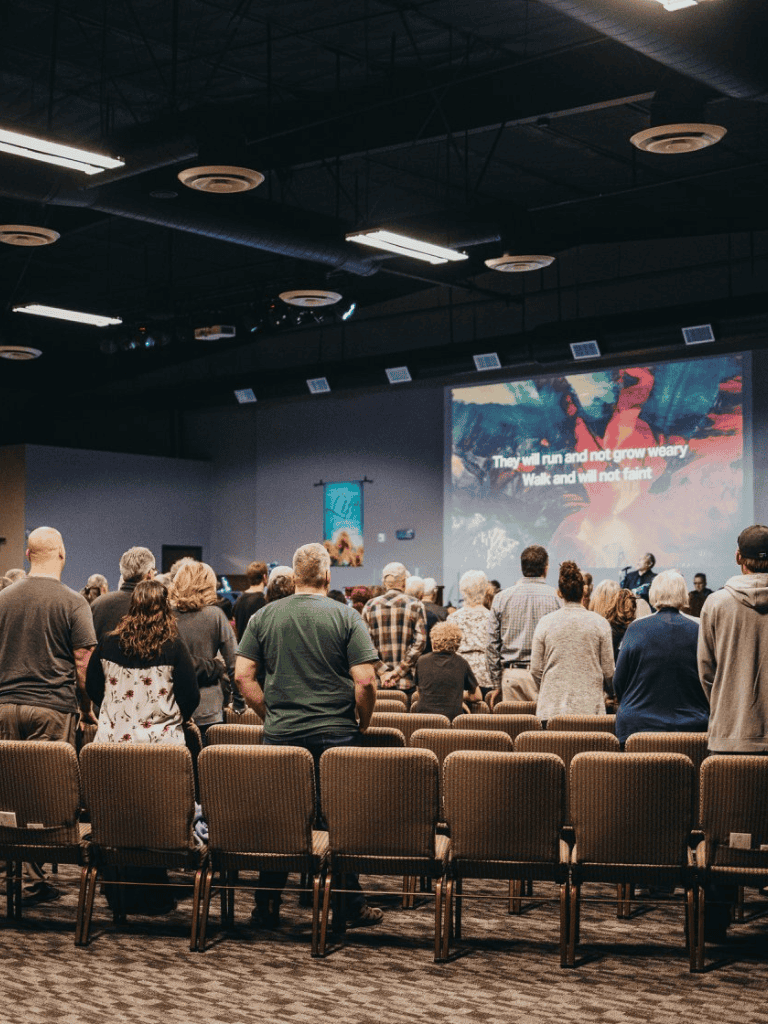 Accessible indoor conference or worship gathering with a diverse audience and inspiring background image.