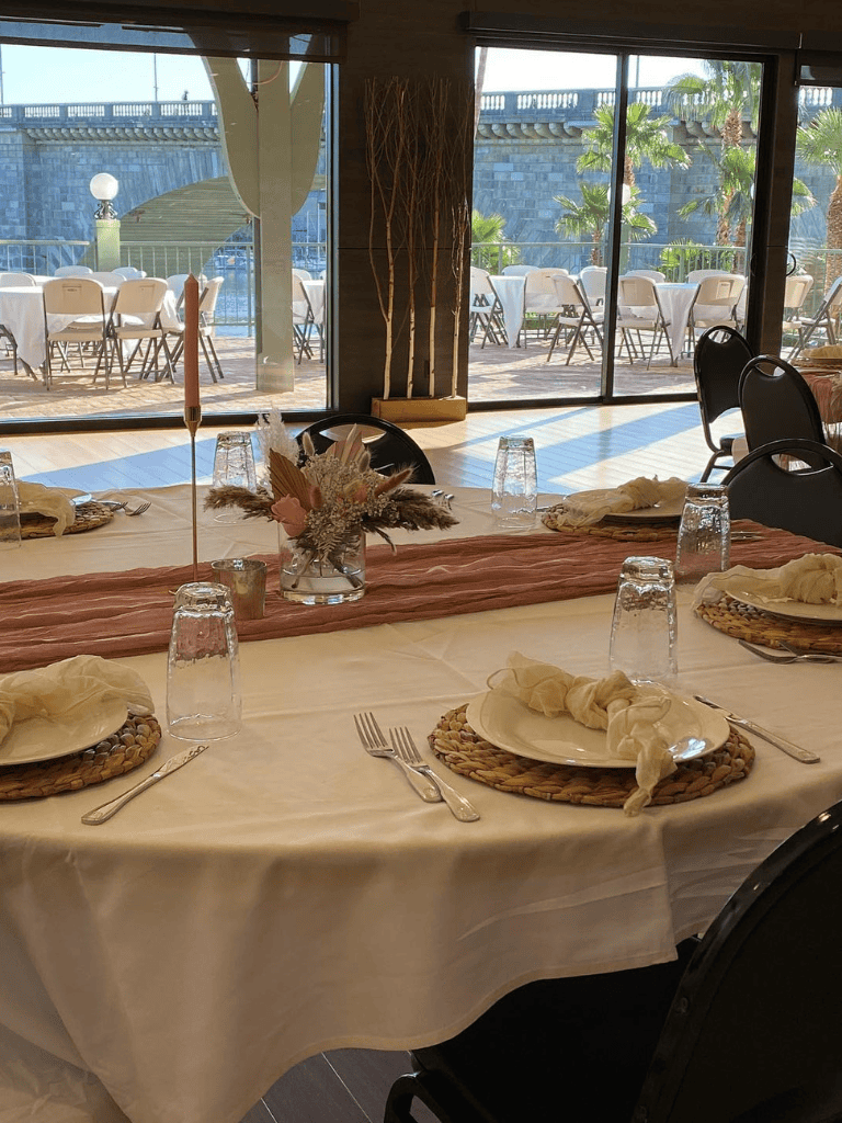 Elegant dining table setup with floral centerpiece, tableware, and scenic waterfront views.