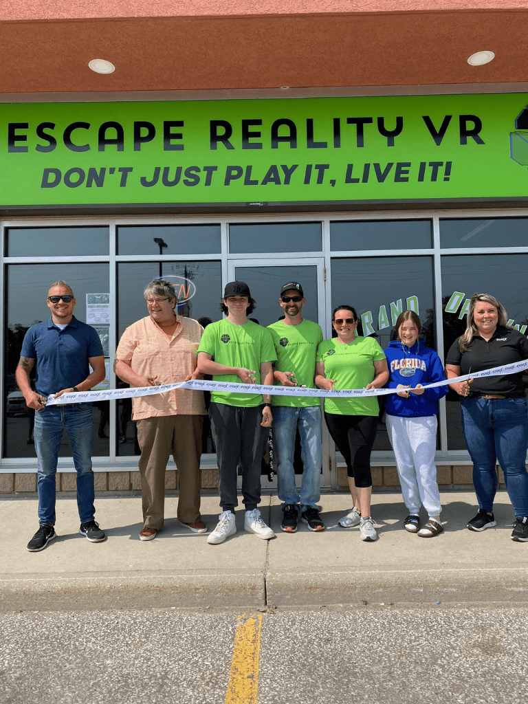 Excape Reality VR store grand opening with team and ribbon cutting, showcasing virtual reality entertainment and experiences.