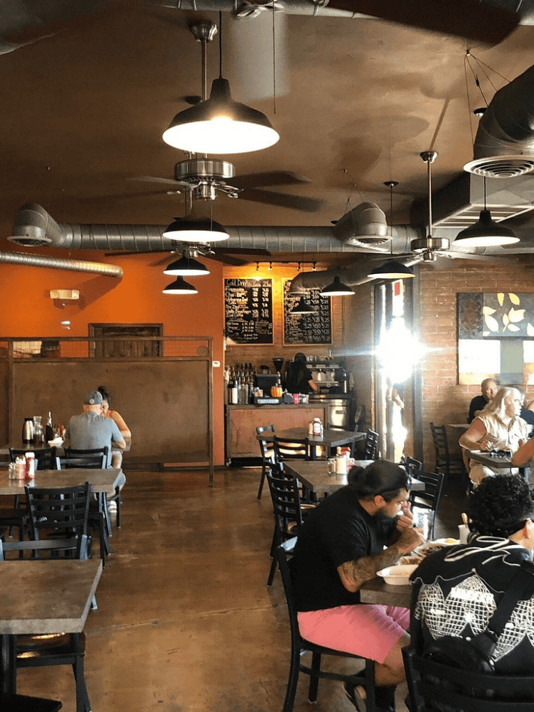 Cozy modern café interior with warm lighting, exposed ductwork, and customers enjoying meals. Perfect for casual dining and coffee.