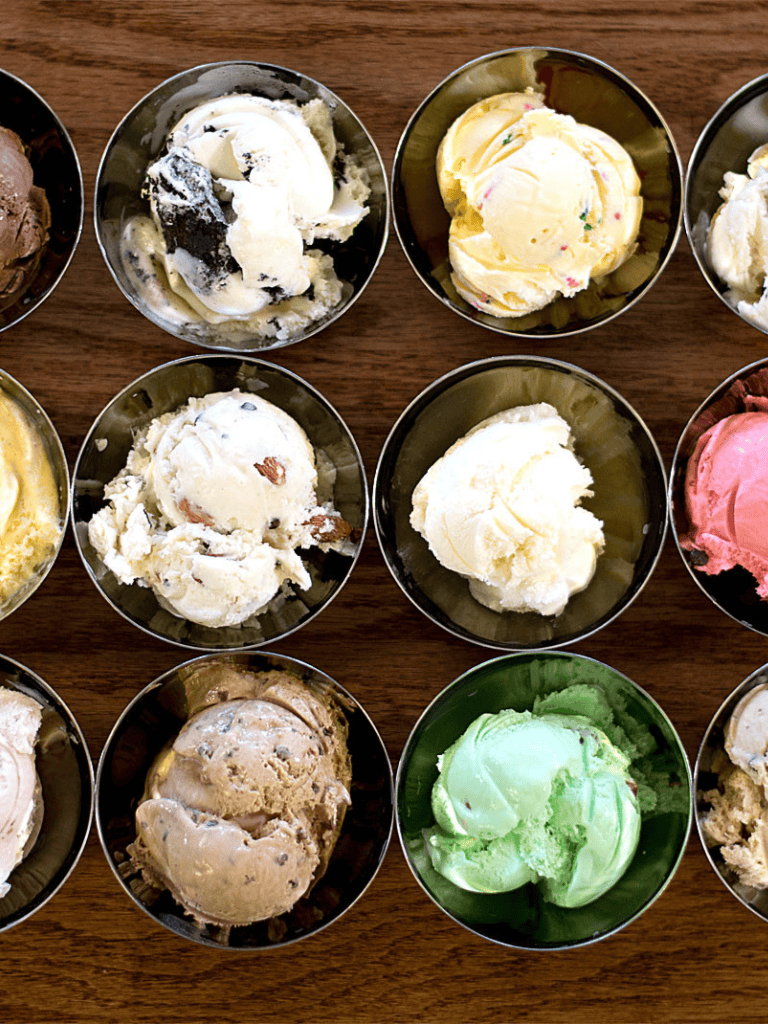 Creamy ice cream scoops in stainless steel bowls on wooden table for dessert.