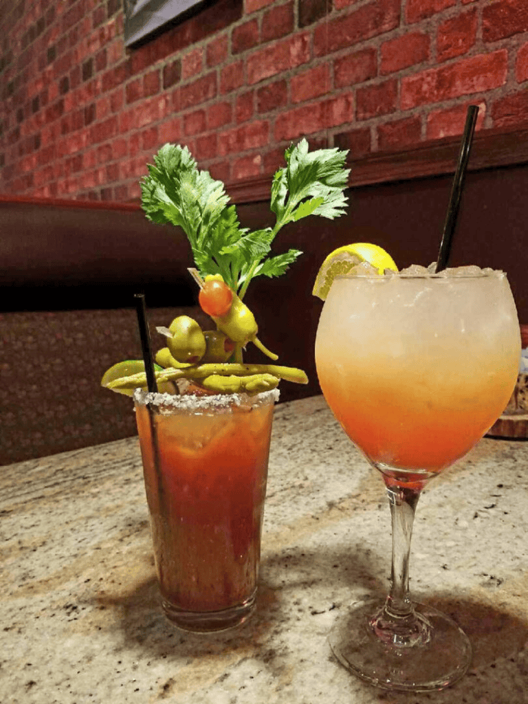 Refreshing cocktail drinks with garnishes on a rustic table at a restaurant.