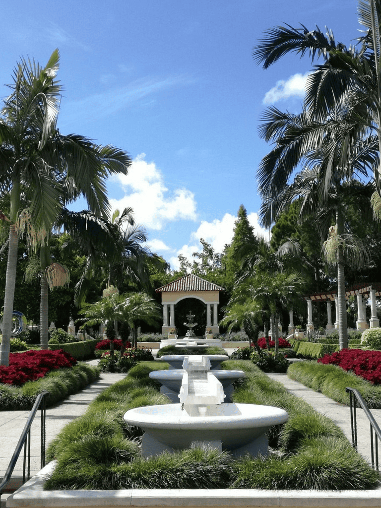 Serene garden with fountains, palm trees, and lush greenery at Quest For Directions.