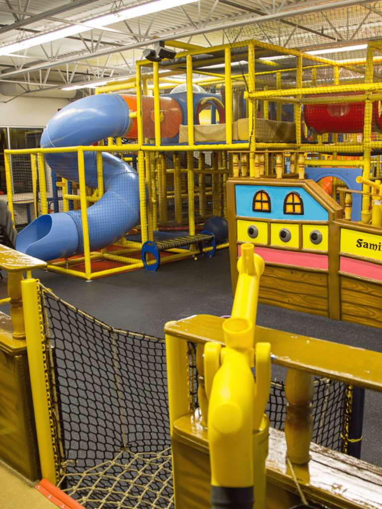 Slide play structure with blue and orange slides, colorful play area for children, indoor playground equipment at QuestForDirections.