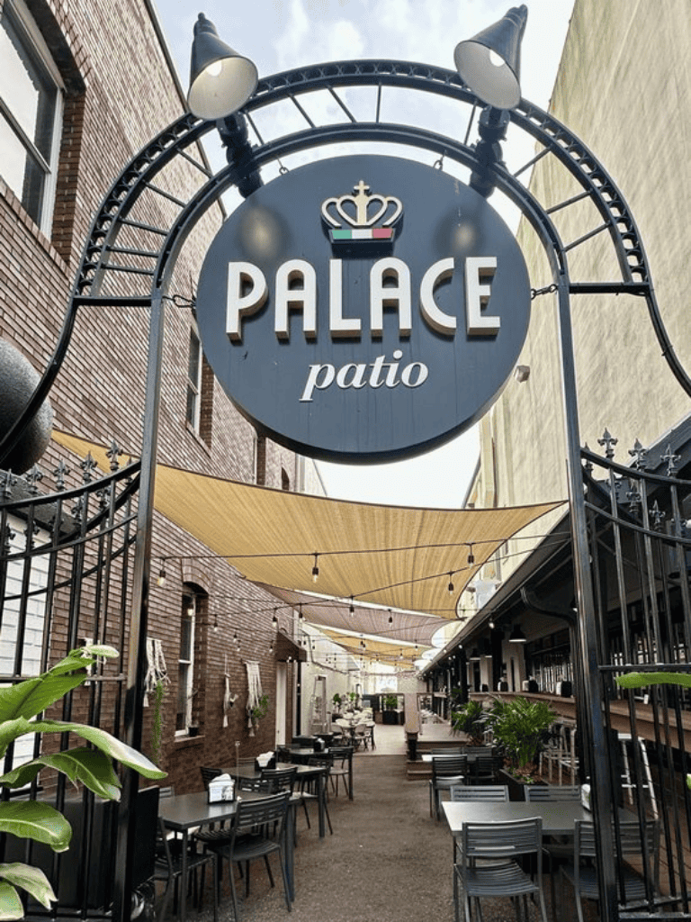 Al fresco dining at Palace patio, an outdoor restaurant with tables, plants, and shaded areas for relaxing meals.