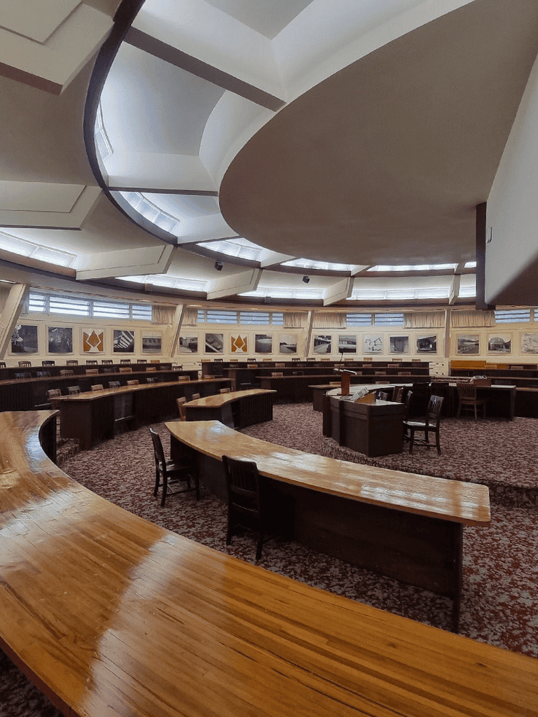 Quiet round conference room with curved wooden tables and modern ceilings, ideal for meetings.