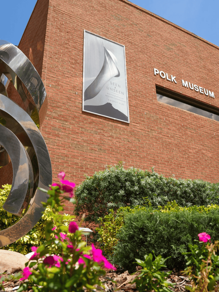 Vibrant flowers and greenery in front of Polk Museum, showcasing art and culture in a scenic outdoor setting.