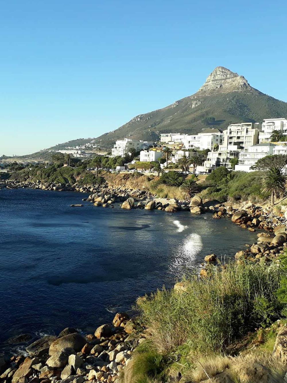 Breathtaking coastal view of the mountains and white modern apartments along the shoreline.