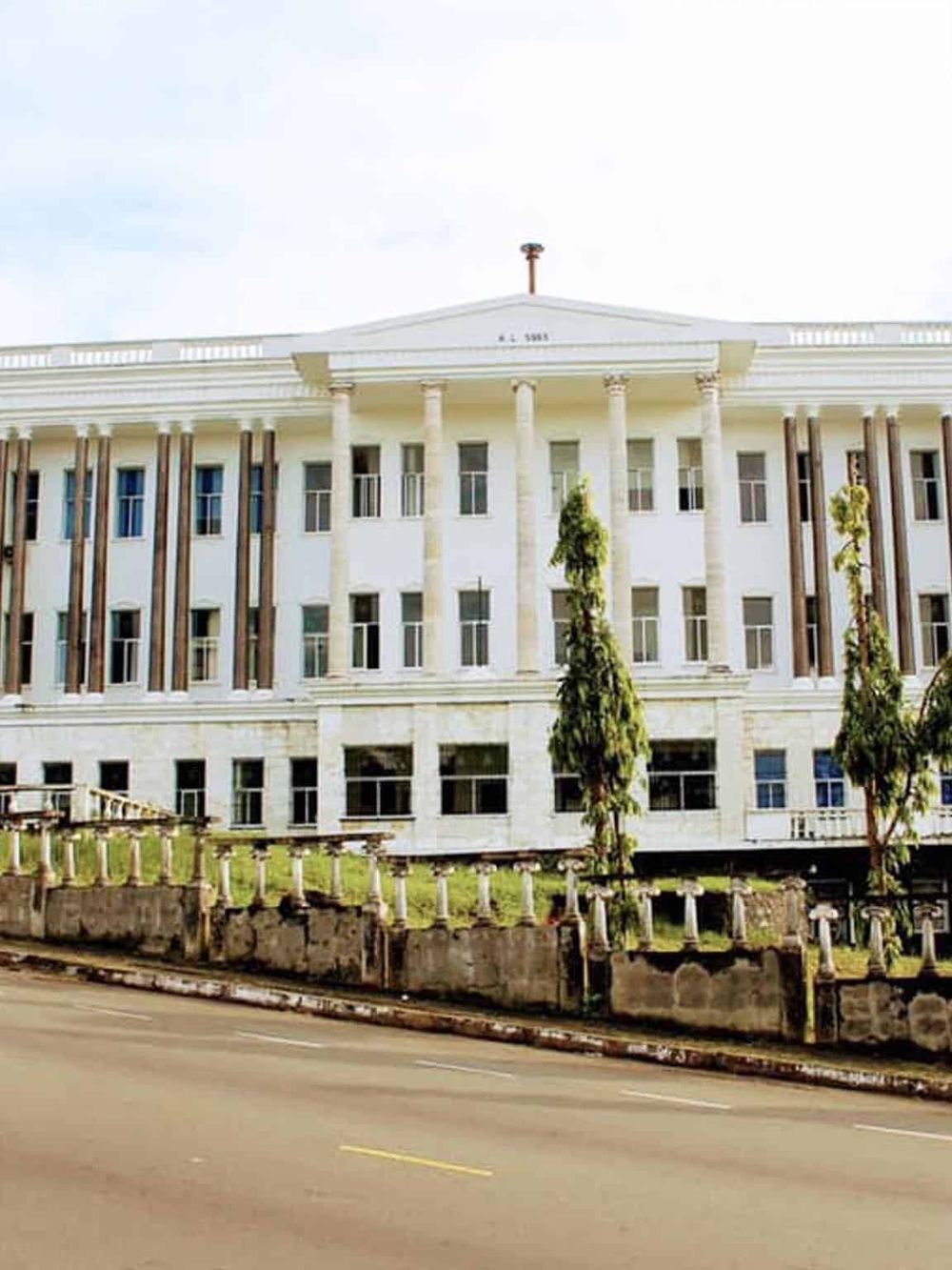 Grand colonial-style government building with tall columns and historic architecture, situated along a street.