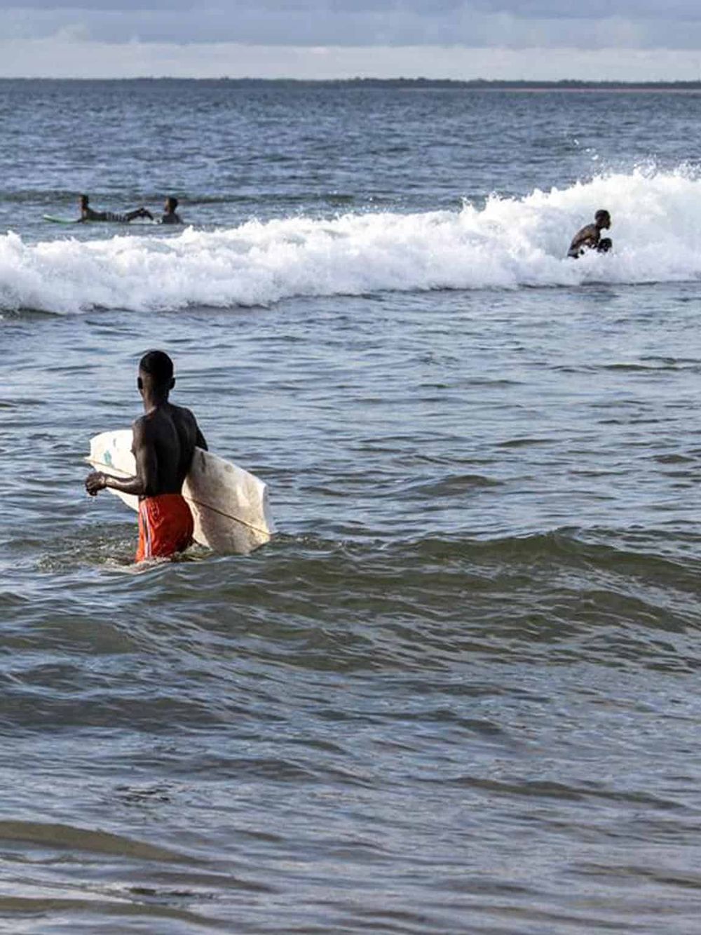Children at the beach enjoying water activities and surfing in the ocean.