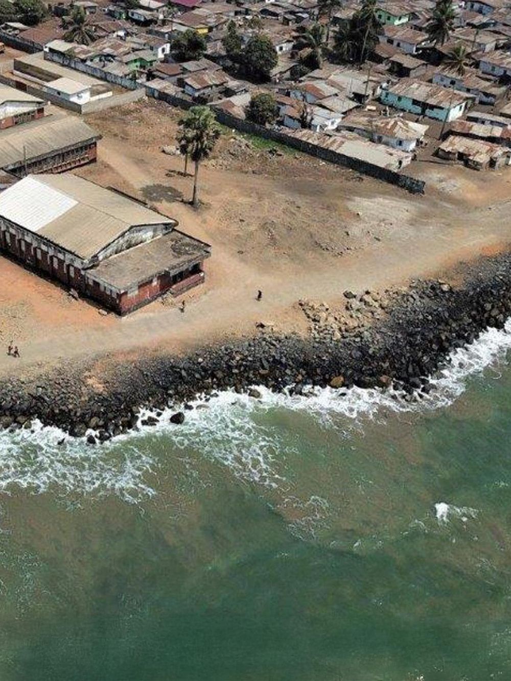 Seaside neighborhood with rocky shoreline and coastal houses, scenic ocean view with crashing waves.