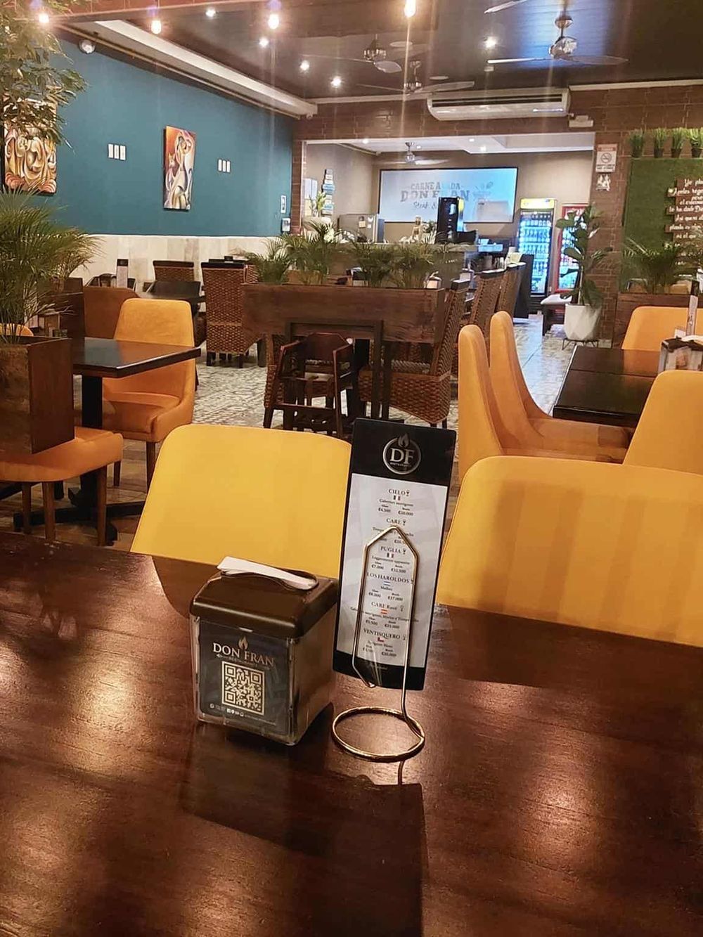 Warmly lit restaurant with yellow and wooden chairs, cozy atmosphere, modern decor, and inviting dining space.