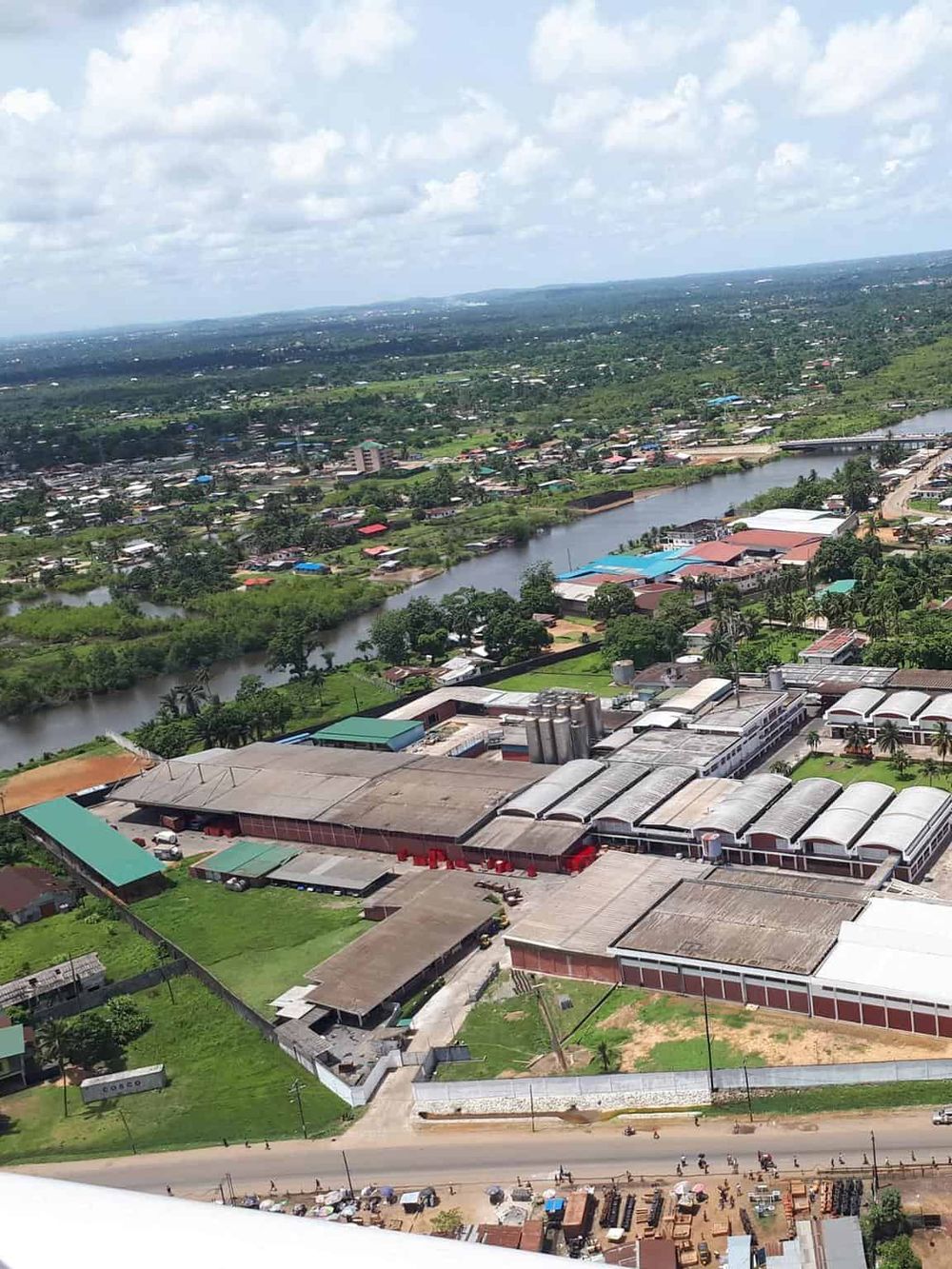 Aerial view of a cityscape with industrial buildings, a river, and lush greenery showcasing urban development and landscape.