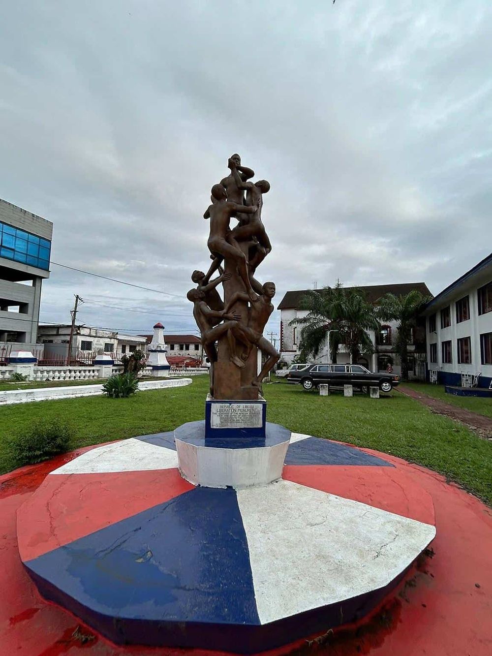 Bronze sculpture of children playing, located in Liberia, celebrating community and childhood.